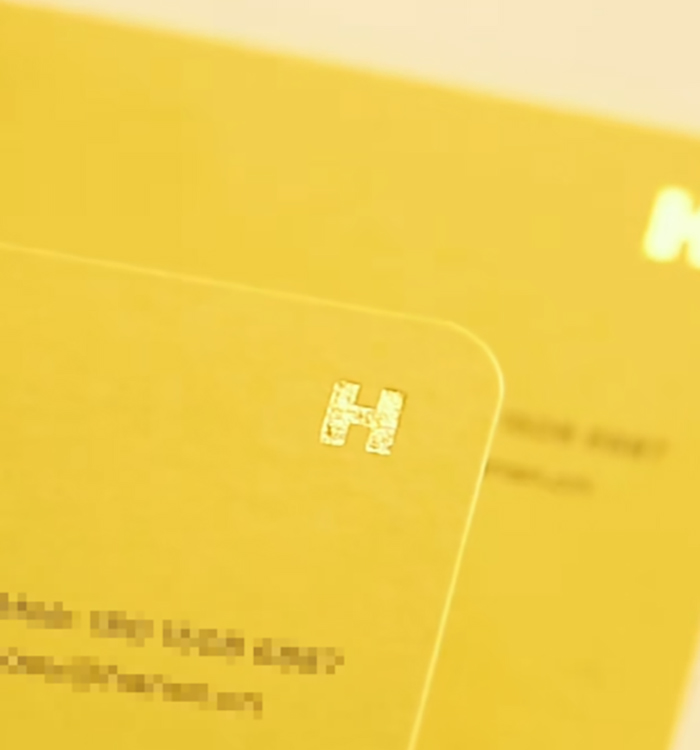 黃色名片上的燙金標誌特寫,展示名片設計的印刷後工序